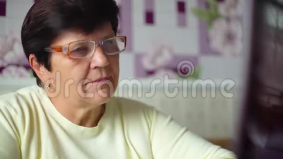 戴眼镜的老年妇女在家里用笔记本电脑上网提供免费和复印空间视频的预览图