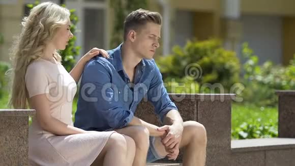 漂亮的金发女孩坐在长凳上拥抱她嫉妒的男朋友怨恨视频的预览图