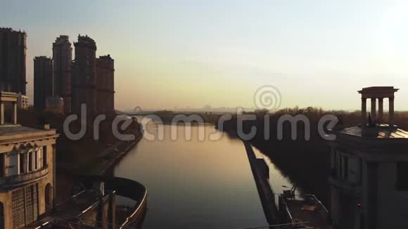 日落时俯瞰河流和大城市飞越摩天大楼和河流视频的预览图