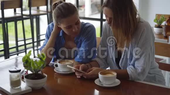 在咖啡馆里约会的女人分享她手机上令人兴奋的东西视频的预览图