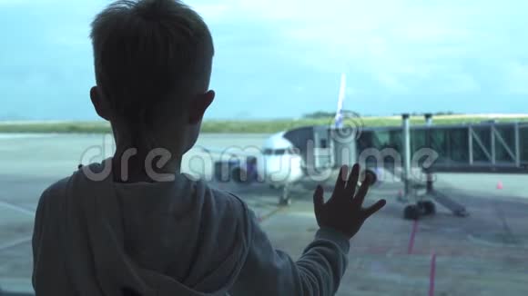 小男孩在候机室等候时从机场窗口看飞机寻找飞机的男孩游客视频的预览图
