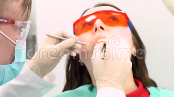 女病人带着医生试图在牙医办公室检查她牙科护理的概念媒体一个年轻女孩视频的预览图