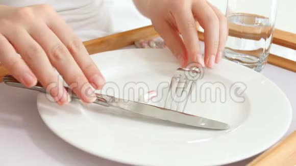 节食妇女用叉子和刀子吃减肥药的4K镜头视频的预览图