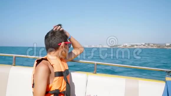 一个戴墨镜的年轻人在海上的船上游泳视频的预览图