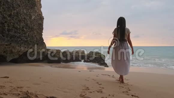 幸福的女人站在沙滩上向天空举手主题是模糊的在洞穴旁边表达喜悦的女人视频的预览图