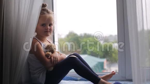 悲伤的女孩坐在窗台上视频的预览图