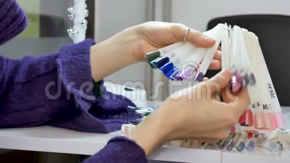 女性手与自然指甲和短指甲选择紫外线指甲样本从调色板视频的预览图