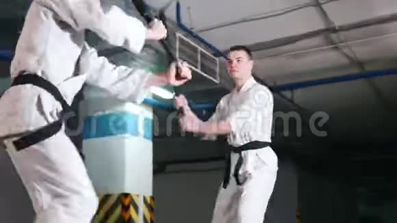 两个穿和服的年轻人在停车场训练剑道剑战视频的预览图
