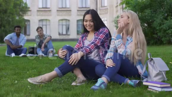 女生看男生调情青少年坐在大学附近的草坪上视频的预览图