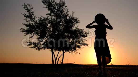 一个穿着长裙的年轻女子站在夕阳下挽着头发的剪影视频的预览图