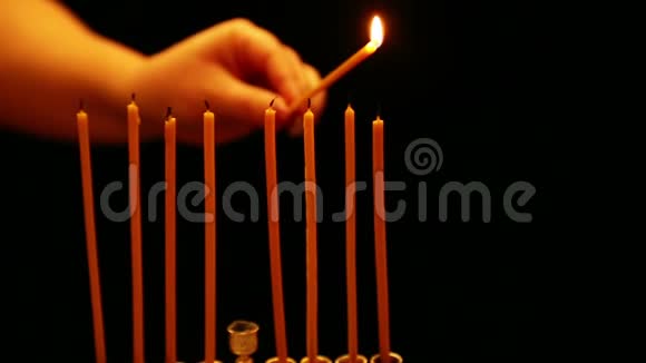 一个女人手里拿着一支蜡烛在光明节的烛台上点燃蜡烛摄像机从右向左移动视频的预览图