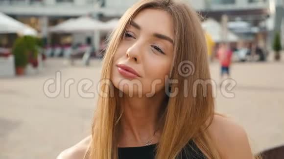 脸浅棕色头发的年轻女人看着镜头近距离城市街头背景的肖像美女视频的预览图