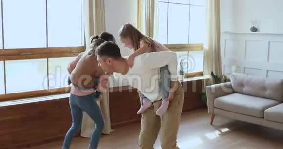 快乐活跃的家庭父母驮着孩子在客厅玩耍视频的预览图