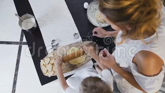 上景小女孩和她的母亲在家里的厨房里捏面团一起做饼干母亲和视频的预览图
