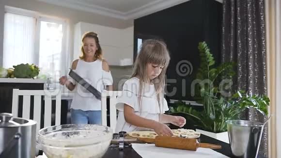 可爱的小女孩用生面团做饼干以心脏和星星的形式漂亮女人把烤盘放在视频的预览图