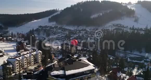 冬季山岭滑雪场的鸟瞰图近山的天空中的气球视频的预览图