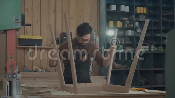 车间里的现代木匠把木制产品的腿连接起来视频的预览图