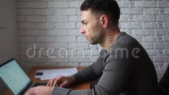一个在办公室里用笔记本电脑工作的年轻人的肖像工作中的自由职业者视频的预览图