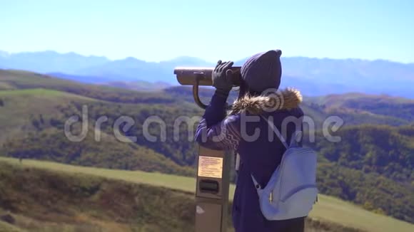 观景台上的旅游女孩用望远镜看着群山慢悠悠视频的预览图