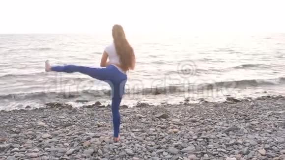 女孩正在做运动在海洋背景上的呼吸练习中腿抬起身体弯曲视频的预览图