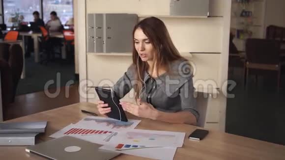 办公室里的一位年轻女士在触摸屏上与商业伙伴交谈视频的预览图
