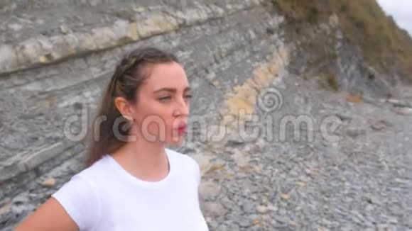 年轻女孩做呼吸练习吸气和呼气身体反射在岩石的背景上分类身体弯曲脸面视频的预览图
