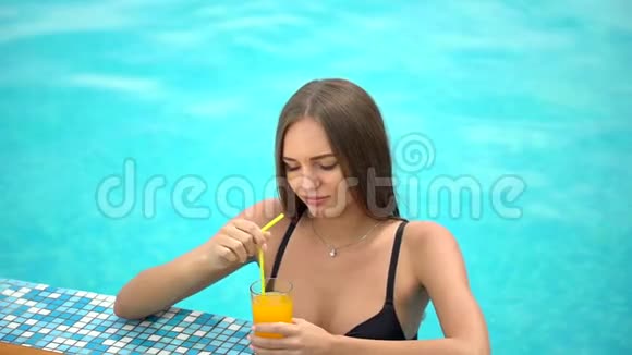 夏天美丽的年轻女子比基尼女孩在热带游泳池放松喝着鲜橙的女人视频的预览图