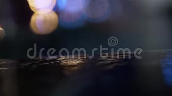 近景雨滴落在水坑上城市人行道上灯光反射视频的预览图