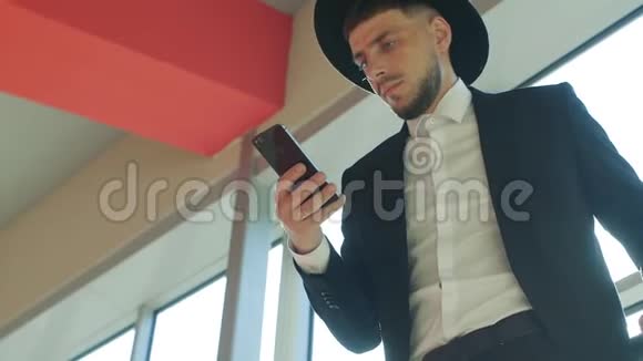 戴着帽子的白人旅行者站在车站看着电话特写镜头慢镜头维奥特视频的预览图