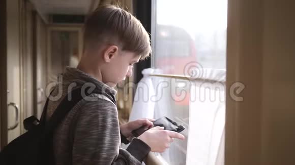 那个男孩站在火车窗口手里拿着一块平板电脑坐火车旅行度假旅游环游世界视频的预览图