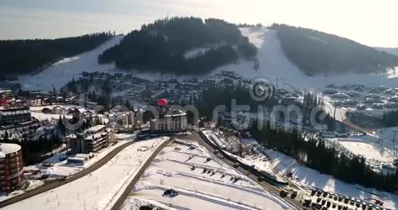 冬季山岭滑雪场的鸟瞰图近山的天空中的气球视频的预览图