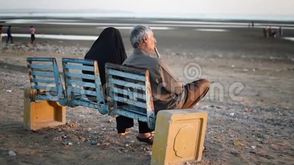 阿拉伯老人夫妇坐在长凳上看着大海视频的预览图
