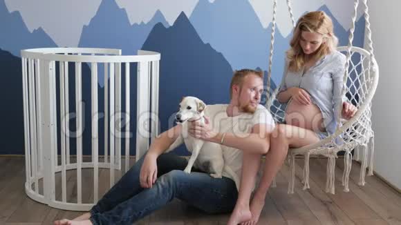 一个年轻的家庭期待着一个孩子和他们的狗杰克罗素玩耍一个女人和一个男人正在玩狗视频的预览图
