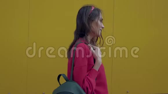 快乐的女人沿着黄色的墙走视频的预览图