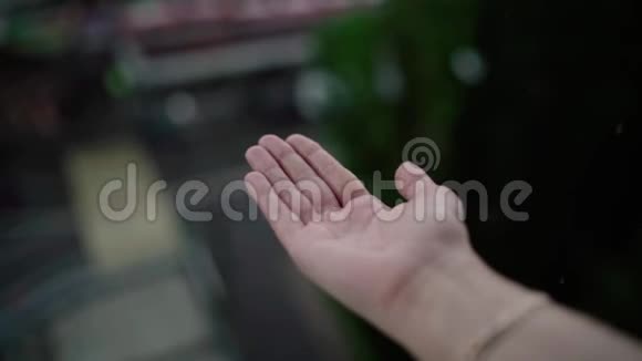 紧紧抓住女人的手在雨中接着雨滴水的概念视频的预览图