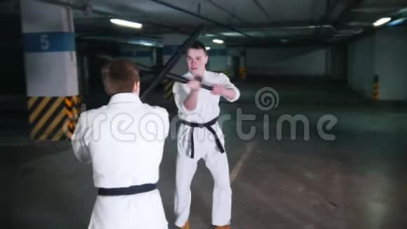 两个穿和服的年轻人在停车场训练剑道视频的预览图