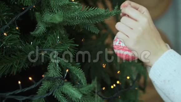 女人把圣诞球挂在树上挂着博克灯一个女人手特写镜头她手里拿着圣诞礼物视频的预览图