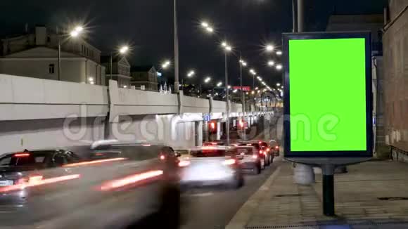 时光流逝有绿色屏幕的广告牌位于一条繁忙的街道上汽车在晚上移动视频的预览图