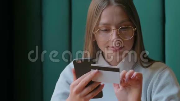 美丽的女性网上银行使用智能手机在线购物与信用卡在家里的生活方式视频的预览图