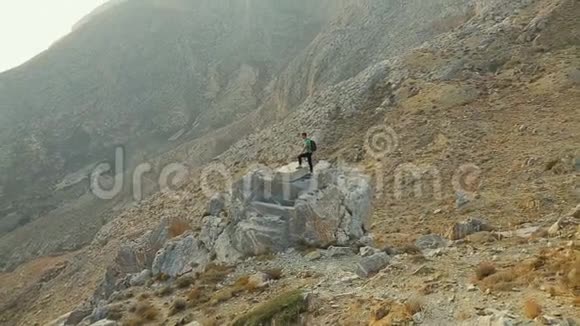 游客站在高高的岩石上享受他的成就审视周围视频的预览图