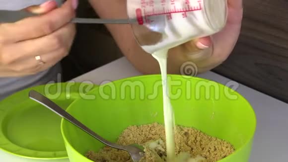 女人在饼干的面包屑中加入炼乳做蛋糕的基本食物视频的预览图
