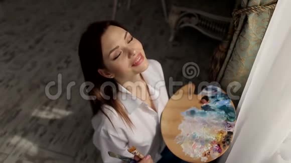 工作室里的女艺术家手里拿着调色板靠近窗户视频的预览图