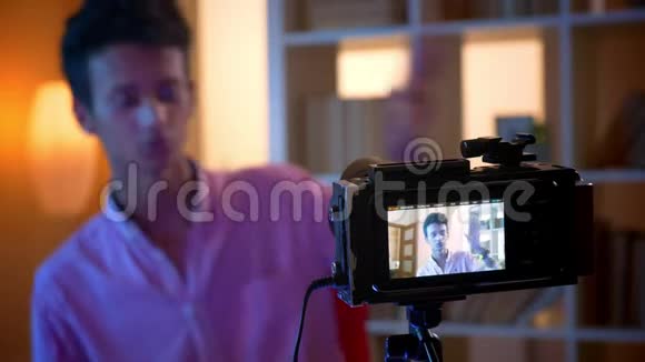 一位年轻迷人的印度男性博客写手在一间舒适的公寓里用摄像机对着室内讲话和打手势视频的预览图