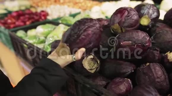 年轻女子在商店货架上选择红色卷心菜一个有魅力的年轻女人手里拿着一种蔬菜视频的预览图