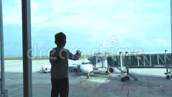 小男孩在机场候机室看着等待的飞机从机场来飞机的小男孩视频的预览图