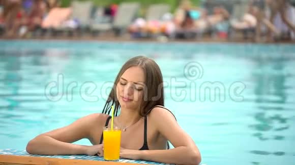 夏天美丽的年轻女子比基尼女孩在热带游泳池放松喝着鲜橙的女人视频的预览图