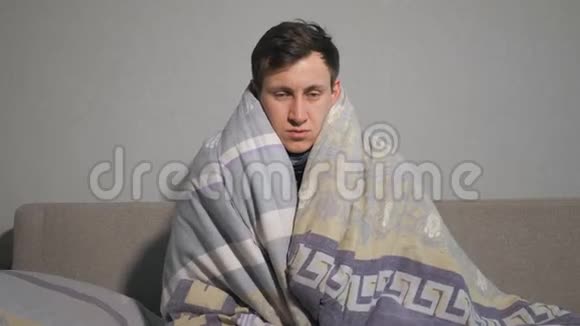 不高兴的年轻人裹在温暖的毯子里视频的预览图