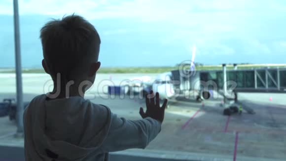 小男孩在机场候机室等飞机时看着窗小男孩从飞机上视频的预览图