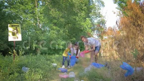 关爱自然生态积极分子的年轻一家带着小女孩在清理大自然的同时把垃圾收集到垃圾袋里视频的预览图