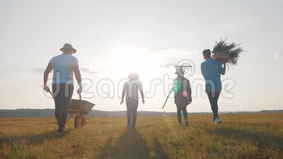 年轻的家庭在他们的农场户外玩得很开心园丁爸爸在日落时推着手推车和蔬菜家庭视频的预览图